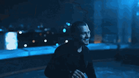 a man is smiling in a dark room with a blurry background .