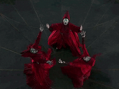 a group of people in red robes are standing in a circle .