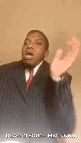 a man in a suit and tie is making a funny face and saying `` deacon young mannnnn '' .