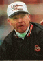 a man wearing a baseball cap and a black jacket with the letter b on the sleeve .