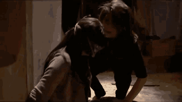 a man and a woman are kneeling down in a dark room and kissing .