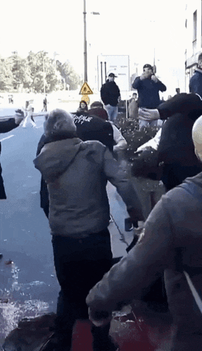 a group of people are standing on a street with a yellow sign that says ' danger ' on it