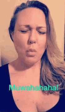 a woman is making a funny face with her eyes closed and the words muwahahaha written on the bottom .