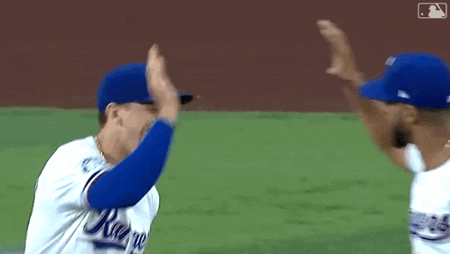 two baseball players are giving each other a high five on the field