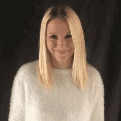 a woman with blonde hair is wearing a white sweater .