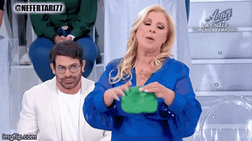 a woman in a blue dress is holding a green purse in front of a man in a white suit