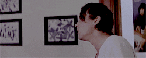 a man in a white shirt is standing in front of a wall with pictures on it
