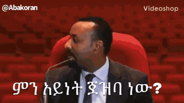 a man in a suit and tie is speaking into a microphone in an auditorium ..