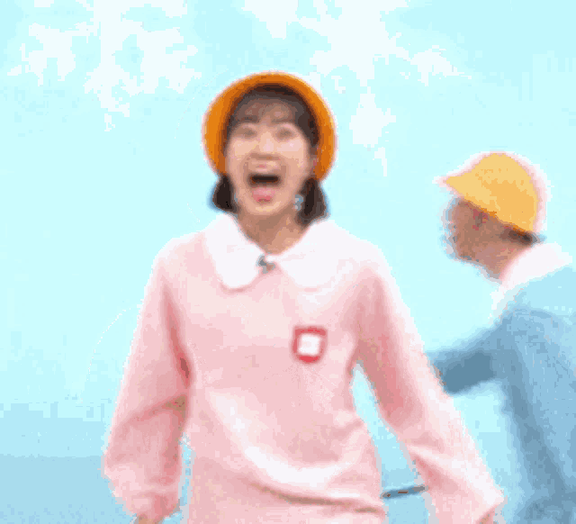a young woman wearing a pink shirt and an orange hat with her mouth open .