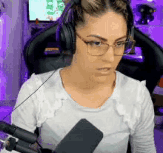 a woman wearing glasses and headphones is sitting in front of a microphone in a room .