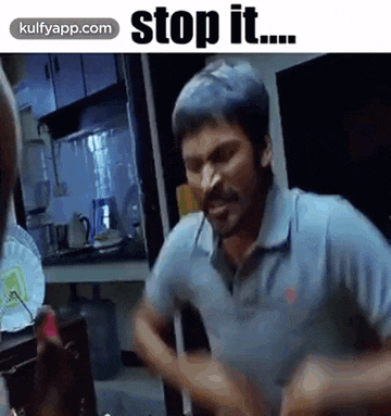 a man is standing in a kitchen with the words `` stop it '' written on the bottom of the image .