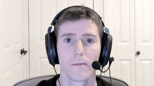 a man wearing headphones and a microphone is sitting in front of a white door .