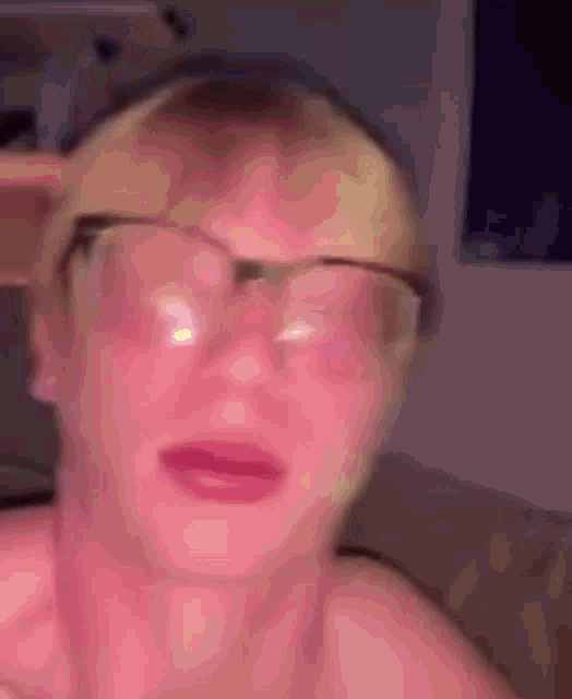 a close up of a person wearing glasses and making a funny face .