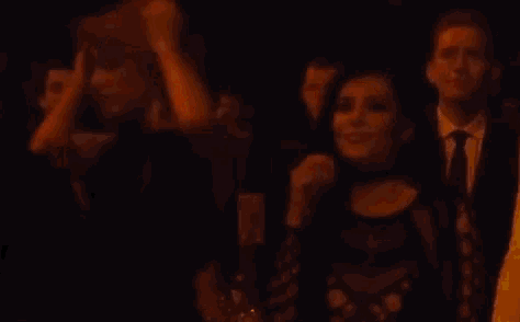 a group of people are standing in a dark room .