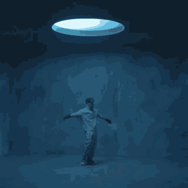 a man stands in a dark room looking up at a light
