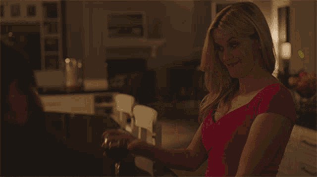 a woman in a red top drinks a glass of wine