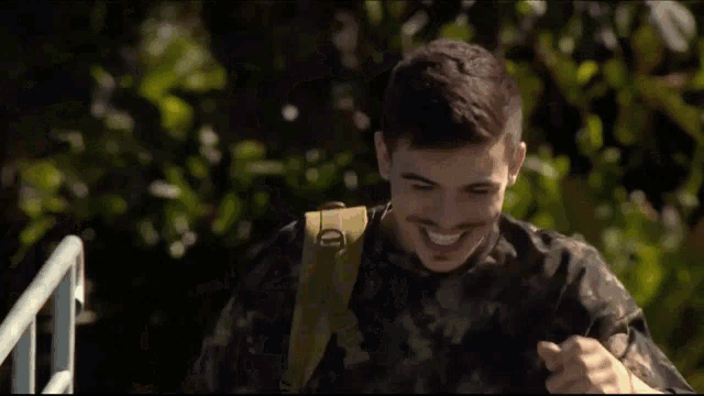 a man in a military uniform is smiling and holding his chest .