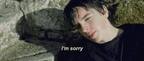 a young man is laying on the ground with his eyes closed and the words `` i 'm sorry '' written above him .