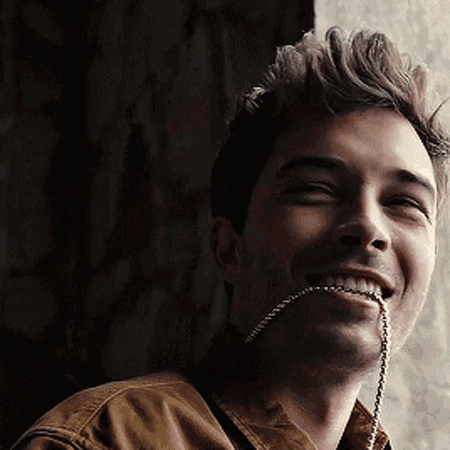 a man with a necklace in his mouth smiles