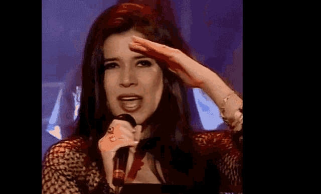 a woman is singing into a microphone while raising her hand in the air .