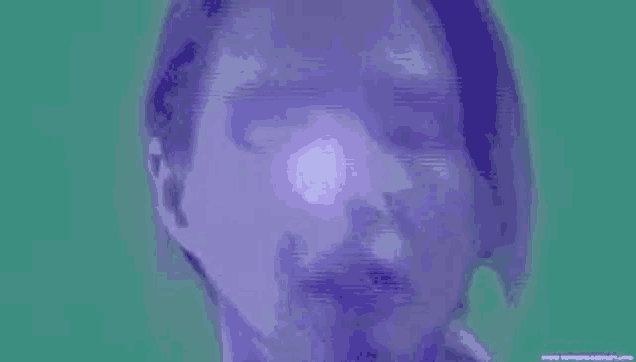 a close up of a man 's face with a purple light shining on it .