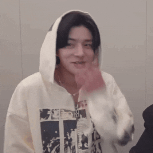 a man wearing a white hoodie is covering his mouth