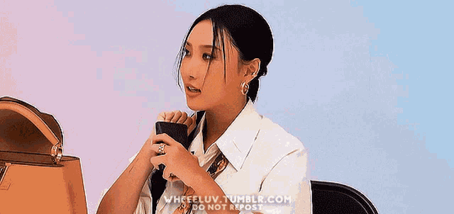 a woman in a white shirt is sitting in a chair holding a cell phone .