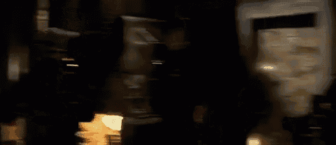 a group of people are standing in a dark room with a painting on the wall .