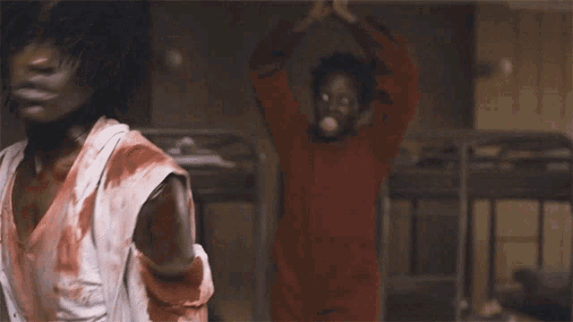 a man and a woman are standing next to each other in a room with blood on their clothes .