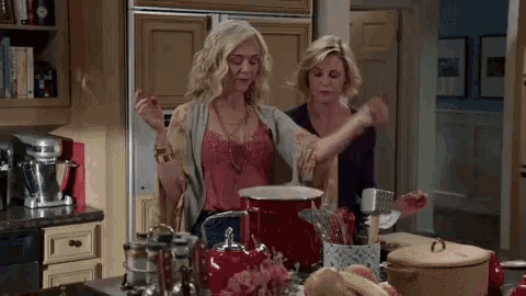 two women are standing next to each other in a kitchen cooking .