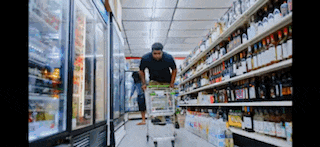 a man is pushing a shopping cart through a grocery store .