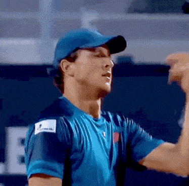a man wearing a blue shirt and a blue hat is flexing his arms