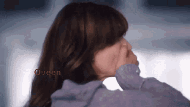 a woman covering her mouth with her hand and the word queen is visible