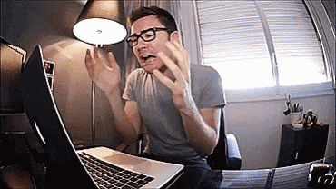 a man with glasses is sitting in front of a laptop