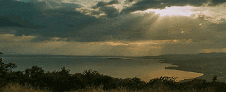 the sun shines through the clouds over a large body of water