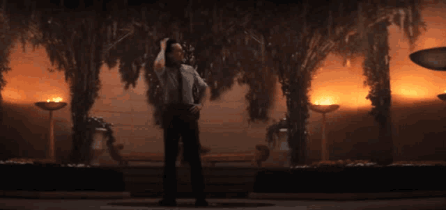 a man in a suit and tie is standing in front of trees