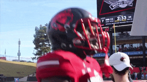 a football player stands in front of a scoreboard that says " wing stop "