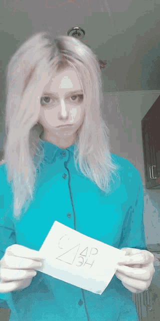 a woman in a blue shirt is holding a piece of paper that says ' czap ' on it