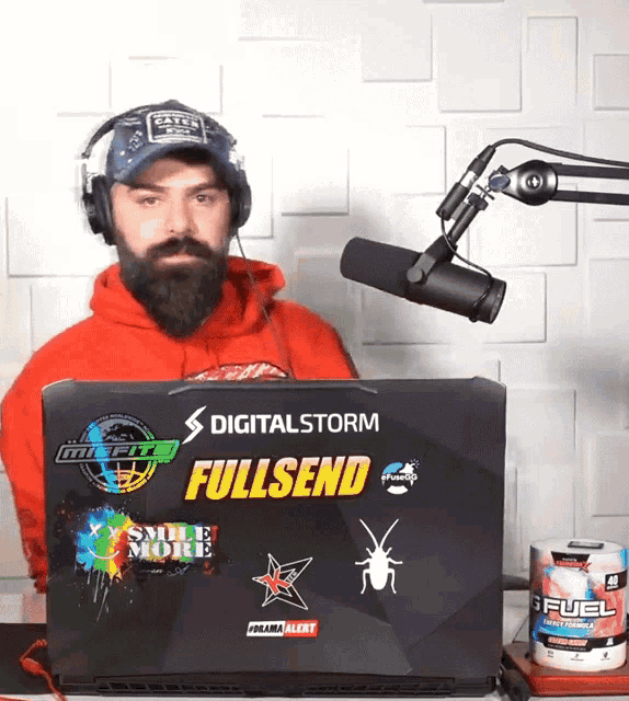 a man wearing headphones sits in front of a laptop that says digitalstorm fullsend