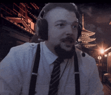 a man wearing suspenders and headphones with the letter s on his shirt