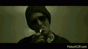 a man wearing sunglasses and a beanie smoking a cigarette .