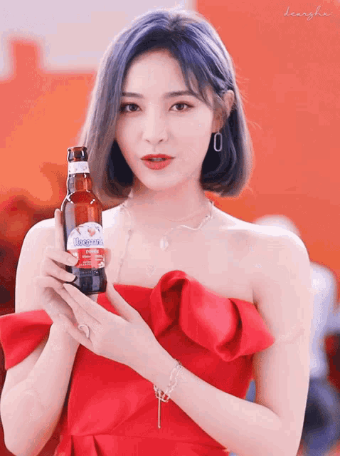 a woman in a red dress holds a bottle of hoegaarden