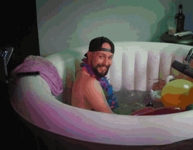 a man with a beard is sitting in a bathtub with a lei around his neck