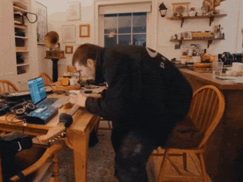 a man sitting at a table with a laptop and headphones on