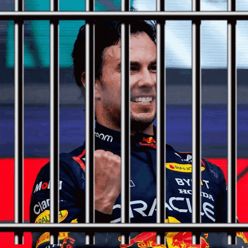 a man behind bars with a red bull racing shirt on