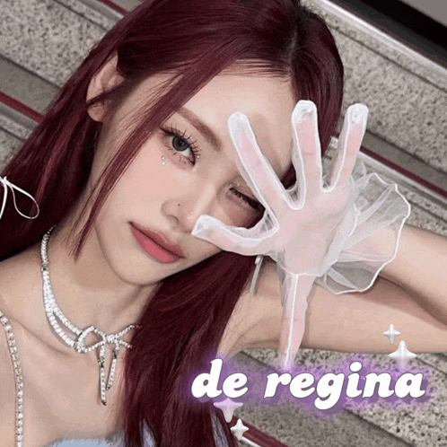 a woman with red hair and a white glove covering her face with the words de regina above her
