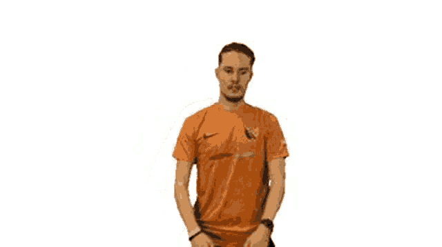 a man wearing an orange nike shirt is holding his hands to his chest .