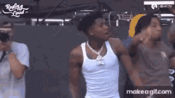 a man in a white tank top is dancing in front of a crowd ..