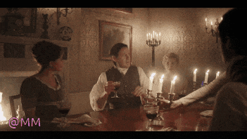 a group of people are sitting at a table with candles and the letters mm on the bottom