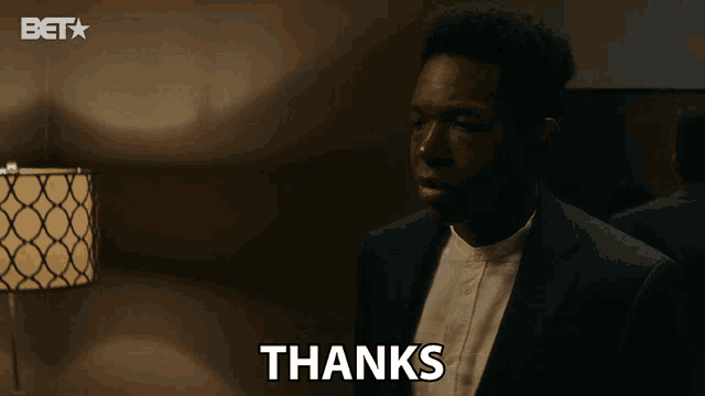 a man in a suit says " thanks " in front of a lamp
